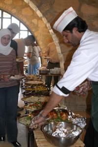 a chef preparing a buffet of food on a table at Dana Guesthouse in Dana