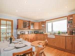 Hebridean View في Trumpan: مطبخ بدولاب خشبي وطاولة مع كراسي