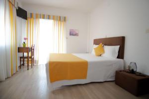 a bedroom with a large bed with yellow and white at Gerês Guest House in Geres