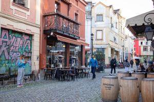 una strada con tavoli e sedie e gente che cammina per la strada di Hotel Dafi a Plovdiv