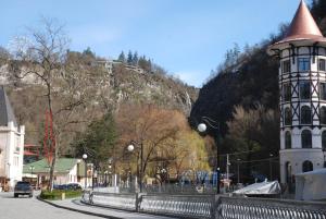 a building with a tower next to a mountain at Borjomi Central Park Apartment in Borjomi