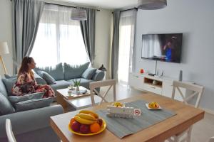 a woman sitting in a living room watching tv at Ralux apartman Tivat in Tivat