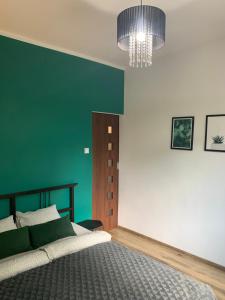 a bedroom with a bed and a green wall at Apartament z widokiem Tarnowskie Góry in Tarnowskie Góry