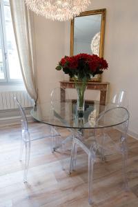 una mesa de cristal con 2 sillas y un jarrón con flores rojas en Design Smart Flat Bordeaux en Burdeos