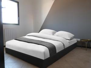 een bed met witte lakens en kussens in een slaapkamer bij Enfin Arrivés ! in LʼIsle-sur-la-Sorgue