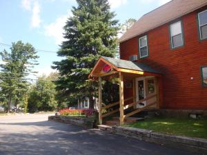 a red brick building with a porch on a street at Maple Leaf Inn Lake Placid in Lake Placid