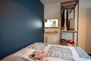 レ・サ​​ーブル・ドロンヌにあるMa Location Sablaise - Appart' Aragoのベッドルーム1室(ベッド1台、壁にテレビ付)
