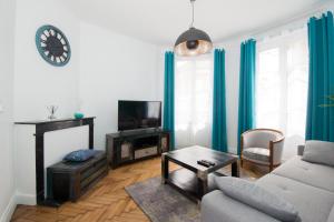 ein Wohnzimmer mit einem Sofa und einem TV in der Unterkunft L'épopée des coteaux 3☆ - centre ville - Epernay in Épernay