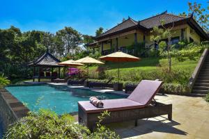 ein Haus mit einem Pool mit einem Stuhl und einem Sonnenschirm in der Unterkunft VILLA CAHAYA Perfectly formed by the natural surrounding and Balinese hospitality in Lovina
