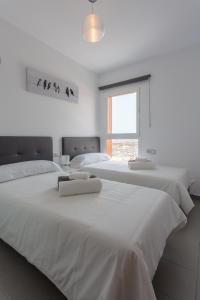 2 camas blancas en un dormitorio blanco con ventana en Mariposas Home Pool en Puerto del Rosario