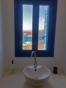 bagno con lavandino e finestra blu di Ftelia Panoramic Sea View Villa Aias a Ftelia