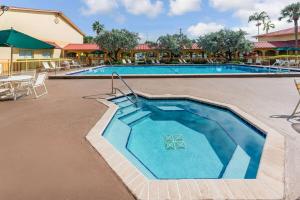 a swimming pool at a resort with blue water at La Quinta by Wyndham Fort Lauderdale Pompano Beach in Fort Lauderdale