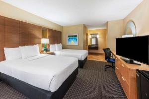 a hotel room with two beds and a flat screen tv at La Quinta by Wyndham Fort Lauderdale Pompano Beach in Fort Lauderdale