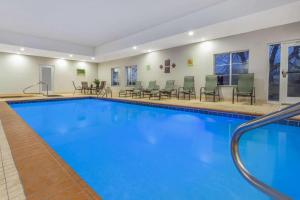 una piscina en un hotel con sillas y mesas en La Quinta by Wyndham Columbus - Edinburgh, en Columbus