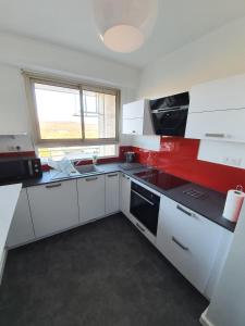 a kitchen with red and white cabinets and a window at L'épopée Panoramique - Parking - Avenue de Champagne - Epernay in Épernay