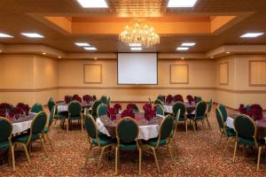 a conference room with tables and chairs and a projection screen at La Quinta by Wyndham Fairbanks Airport in Fairbanks