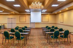 una sala de conferencias con mesas y sillas y una pantalla de proyección en La Quinta by Wyndham Fairbanks Airport, en Fairbanks