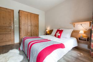 a bedroom with a large bed with a red and white blanket at Résidence La Chaumière in Les Gets