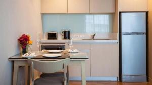 
a kitchen with a table and a refrigerator at Amari Residences Bangkok - SHA Plus in Bangkok
