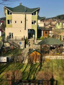 een groot wit huis met een tuin met bomen bij ЯрДана in Skhidnitsa