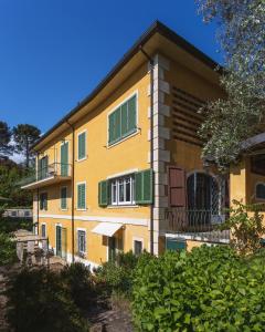een geel gebouw met groene luiken erop bij Villa Borgovecchio B&B in Camaiore