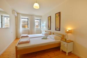 a bedroom with a bed and a lamp and two windows at Bonagrazia in Corfu Town