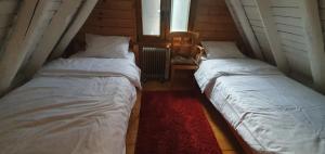 two twin beds in a room with a red rug at Traditional Casa Pescarului langa lac cu ponton in Colibiţa