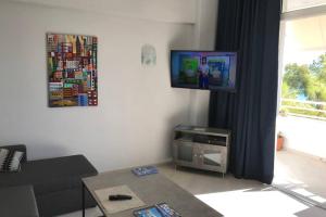 salon z kanapą i telewizorem z płaskim ekranem w obiekcie Sea view apartment w mieście Lutraki