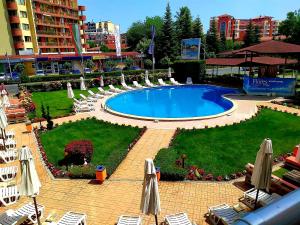 a swimming pool with lawn chairs and umbrellas at Flores Park in Sunny Beach