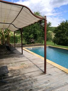 a wooden deck with a canopy next to a swimming pool at La Petite Vignolle in Saint-Amand-de-Coly