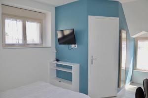 a bedroom with a blue wall with a bed and a tv at La petite maison 3 in Avoine