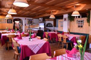 restauracja ze stołami i krzesłami z różowymi obrusami w obiekcie Appartamenti Astoria La Villa w mieście La Villa