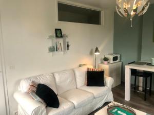 una sala de estar con un sofá blanco con almohadas. en Le studio de la Villa Madeleine, en Spa