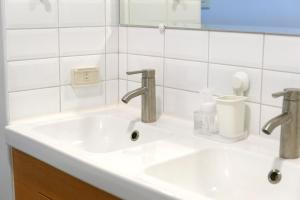 a bathroom sink with two faucets and a mirror at Ren Homestay in Hengchun