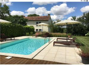a swimming pool with two chairs and an umbrella at LE TEXIER The Cottage in Verteillac