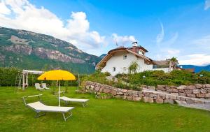 un parapluie jaune, deux chaises et une maison dans l'établissement Villa Trogerhof, à Ora