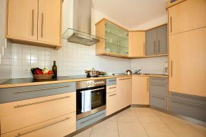 La cuisine est équipée de placards en bois et d'un four avec plaques de cuisson. dans l'établissement Villa Trogerhof, à Ora