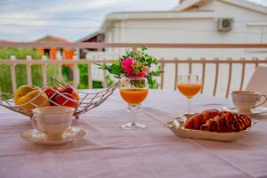 a table with two glasses of orange juice and a basket of fruit at APARTMENT TONY - 2bdr Beachfront in Jadrija