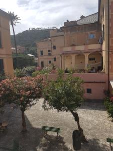 un bâtiment avec deux arbres et un banc dans une cour dans l'établissement Albergo Lungomare, à Bonassola