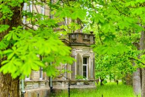 an old building with a window in the middle of trees at Admirala nams in Liepāja