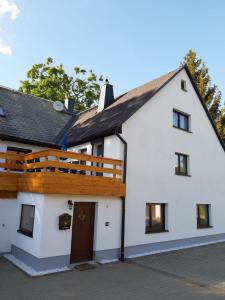 Casa blanca con techo de madera en Familienfreundliche Ferienwohnung, en Zschorlau