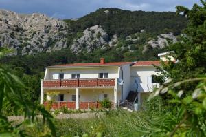a white house with a mountain in the background at Apartments Aneva in Baška