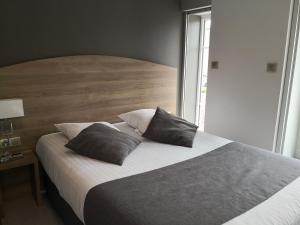 ein Schlafzimmer mit einem großen Bett mit zwei Kissen darauf in der Unterkunft Hotel du Commerce in Châtillon-sur-Chalaronne