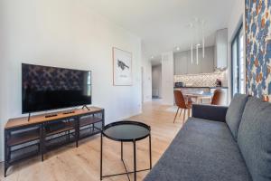 a living room with a couch and a flat screen tv at Apartamenty Sun & Snow Aura III in Gdańsk