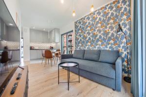 a living room with a blue couch and a kitchen at Apartamenty Sun & Snow Aura III in Gdańsk