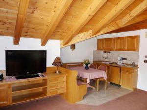 ein Wohnzimmer mit einem großen TV und einer Küche in der Unterkunft Haus Central Oberstdorf in Oberstdorf