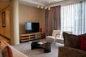 uma sala de estar com um sofá e uma televisão em Raphael Suites em Joanesburgo