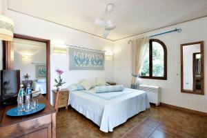 a bedroom with a white bed and a television at Arbatax Park Resort - Ville del Parco in Àrbatax