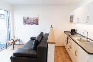 a living room with a black couch in a kitchen at AMBERG APART - Apartment B - Wohnraum auf Zeit in Amberg