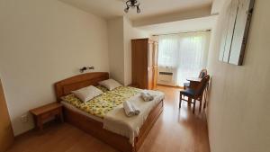 a bedroom with a bed and a chair and a window at Apartmán TATRAN Jarka in Donovaly